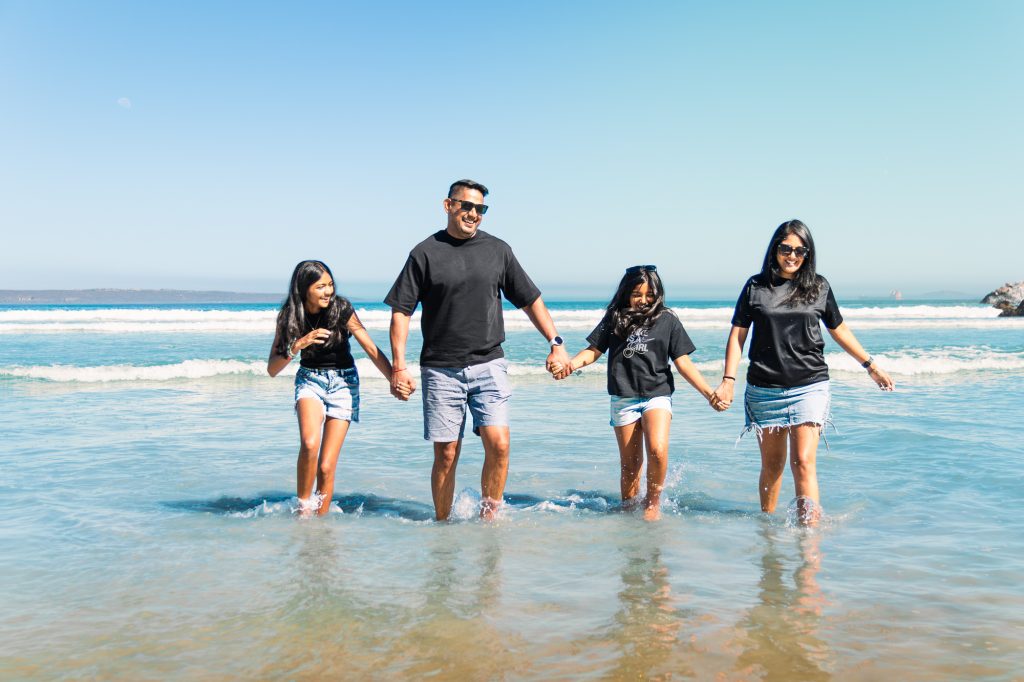 Excited family splashing in shallow water at the beach as a natural prompt pose