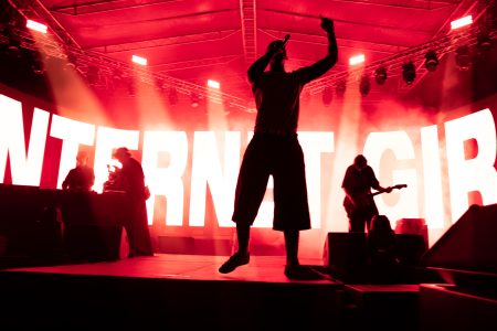 Moody red lighting silhouettes the singer as he entertains the crowds at a music festival