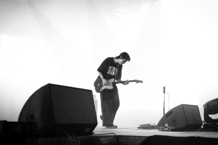 Harsh contrast black and white photo of punk musician playing the guitar on stage